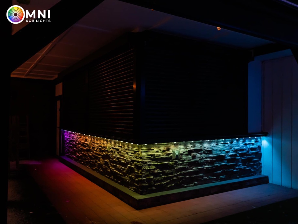 Blue, purple, and green permanent lighting on a commercial stone wall